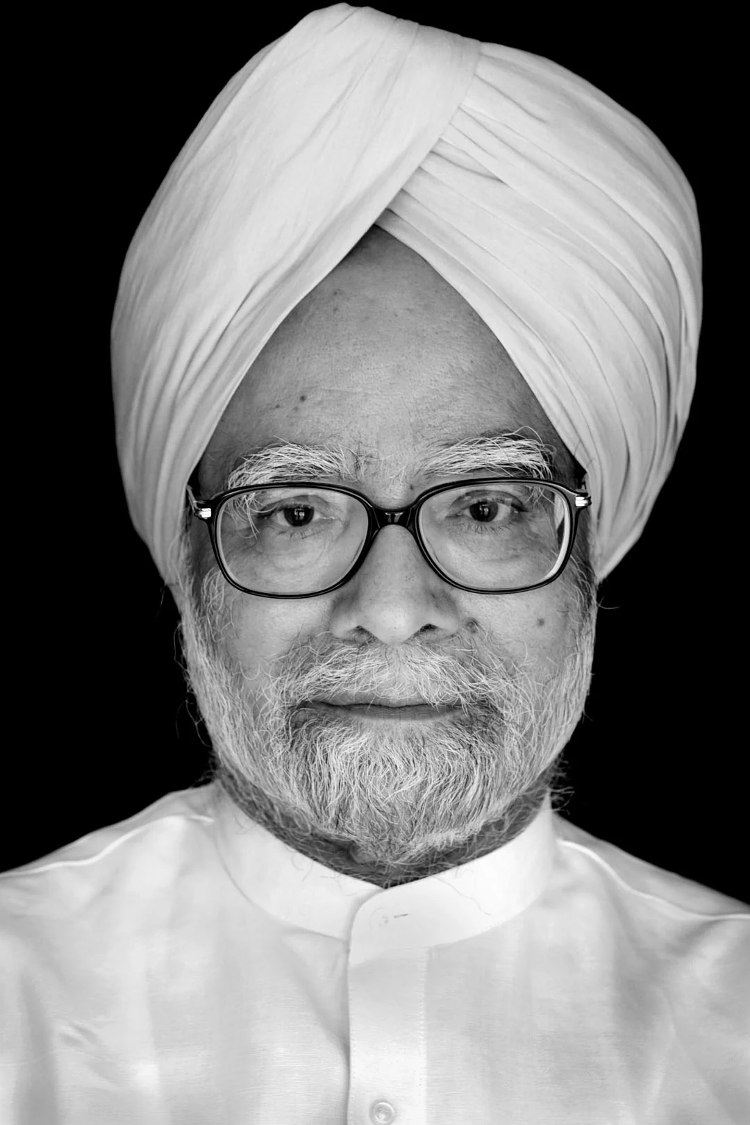 A black-and-white portrait of Manmohan Singh wearing a white turban and glasses.